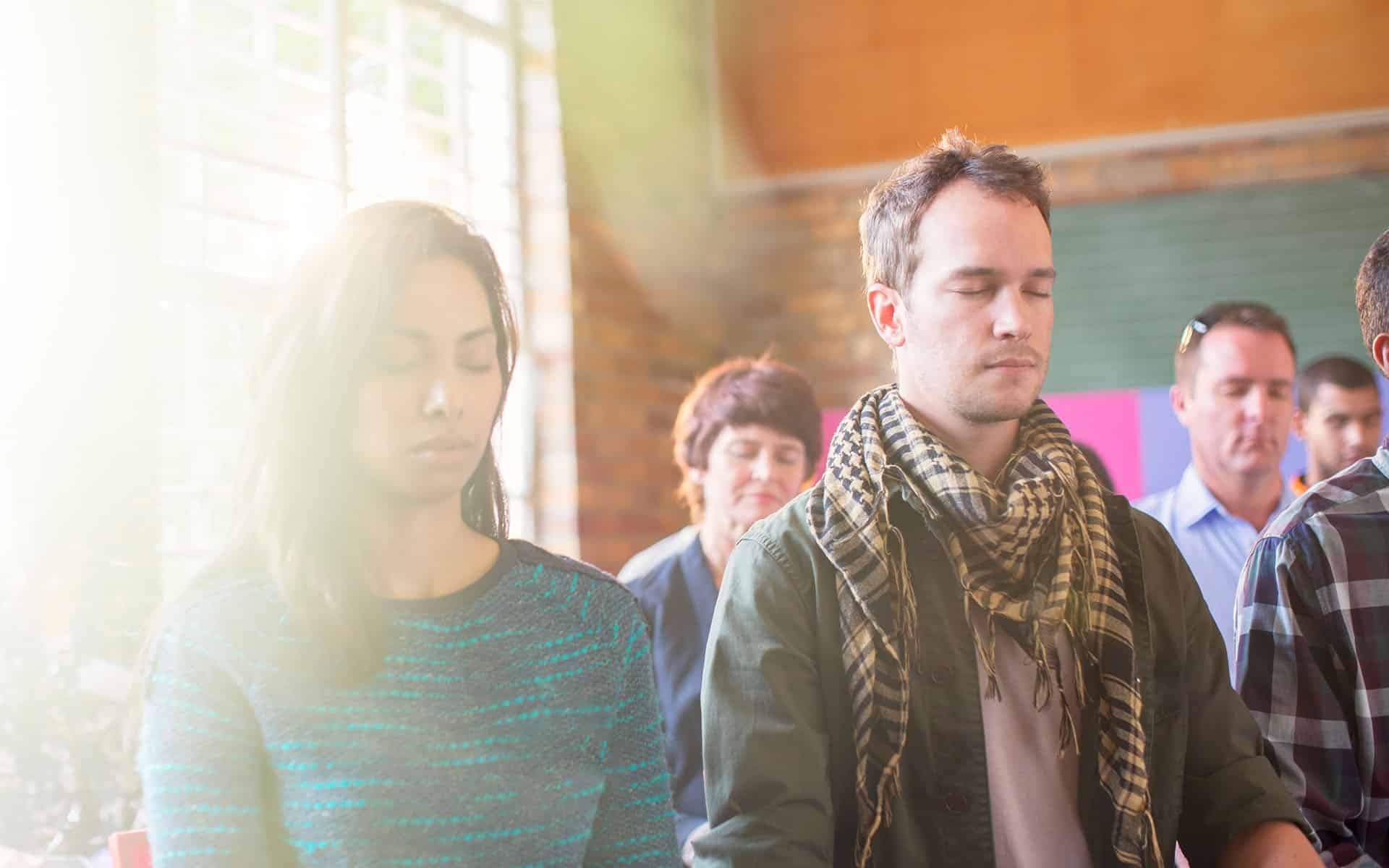 Serene people with eyes closed meditating together