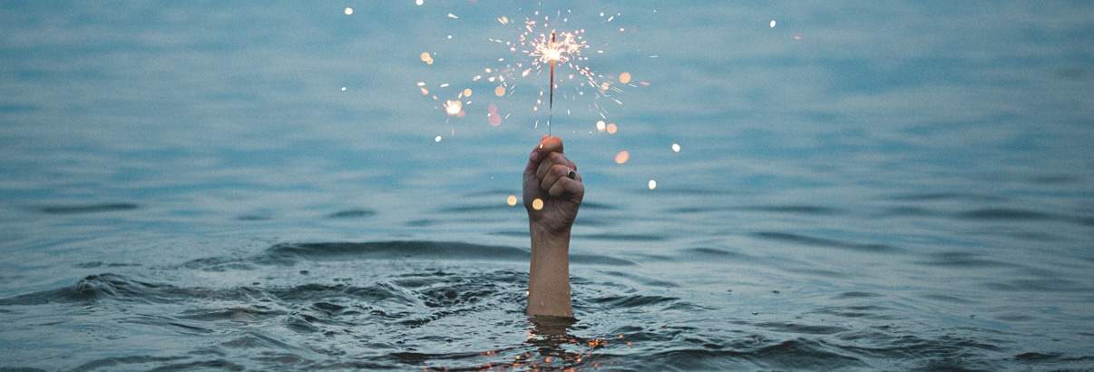 hand holding sparkler coming out of the water. setbacks