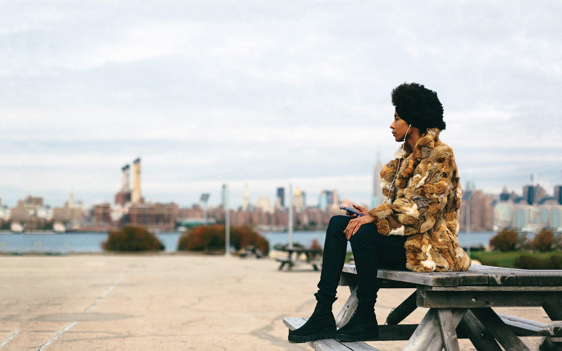 woman in vintage fur coat sitting on bench