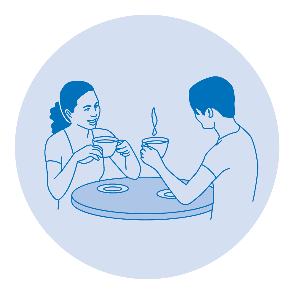 Two people sitting at a table drinking coffee or tea together.